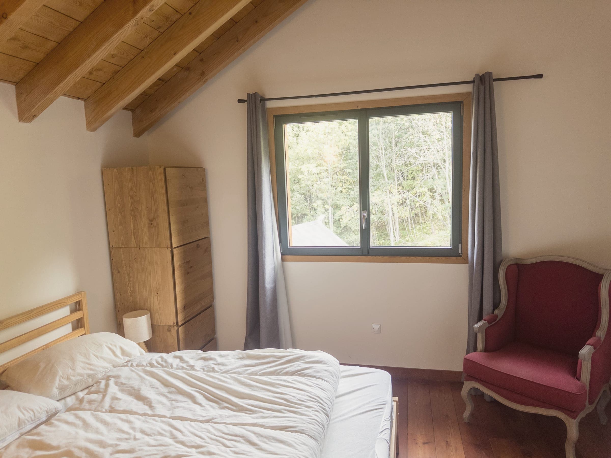 Chambre 2 sous les combles : lit double, armoire en bois et fauteuil