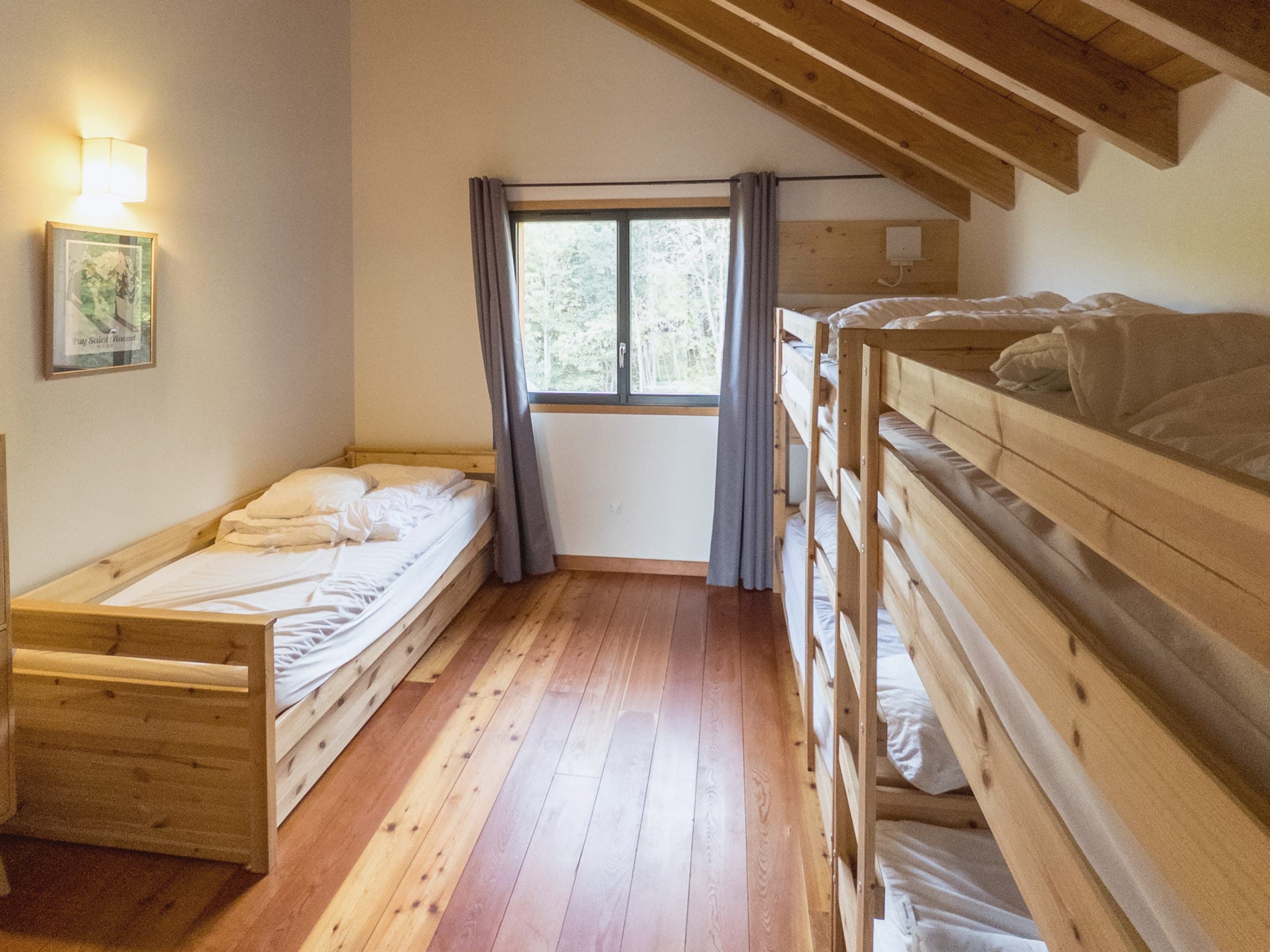 Le dortoir sous la charpente : lits superposés et lit simple