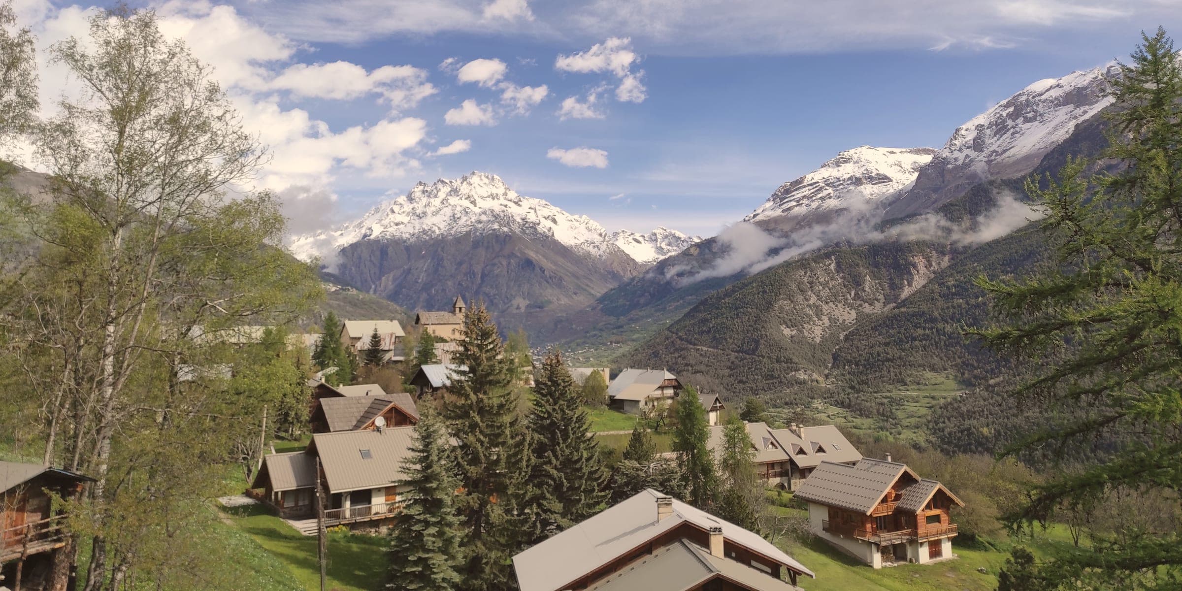 La vue du chalet en été : le village, la vallée et les sommets enneigés