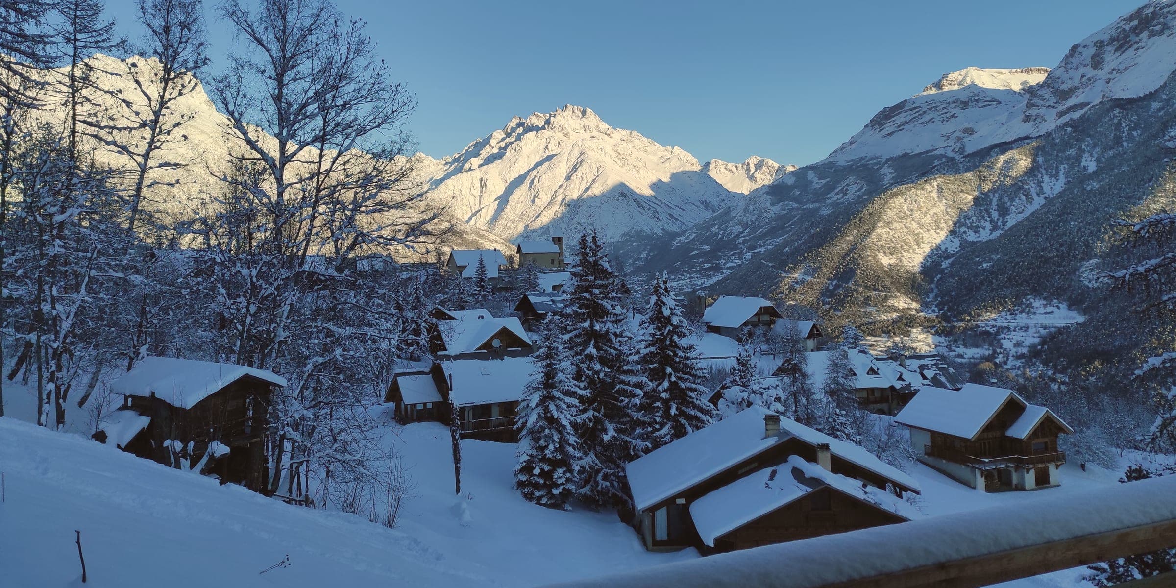 La vue du chalet en hiver : le village et la vallée sous la neige
